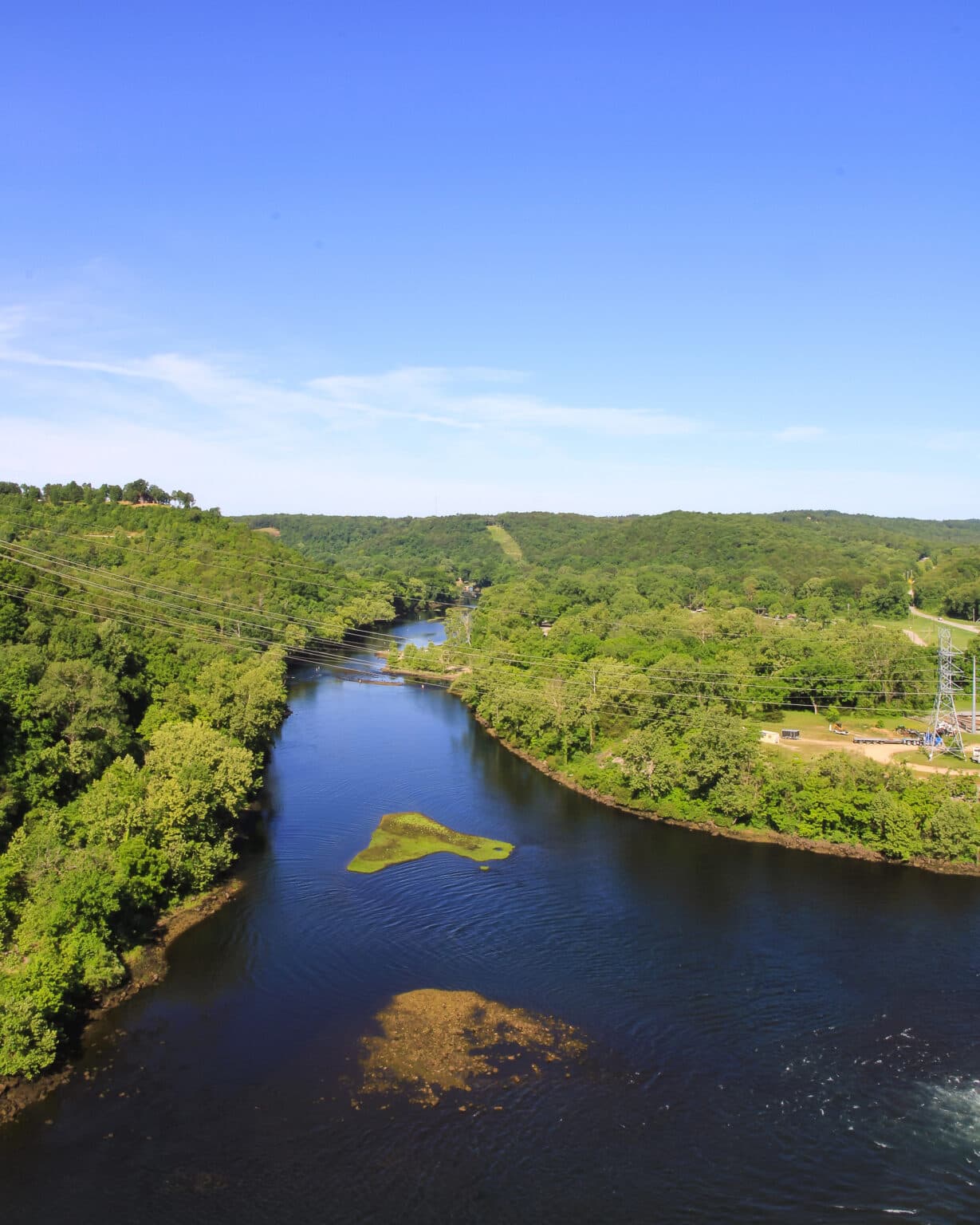 A serene river winding through lush green hills under a clear blue sky.