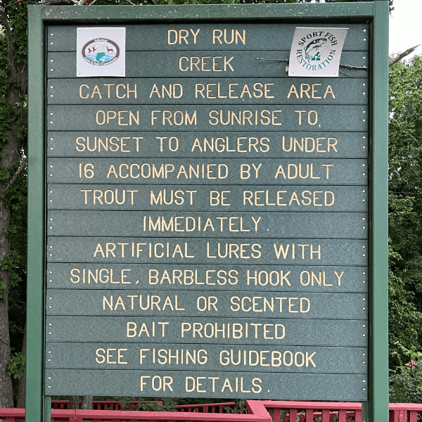 A sign detailing fishing regulations for Dry Run Creek, emphasizing catch and release rules and bait restrictions.